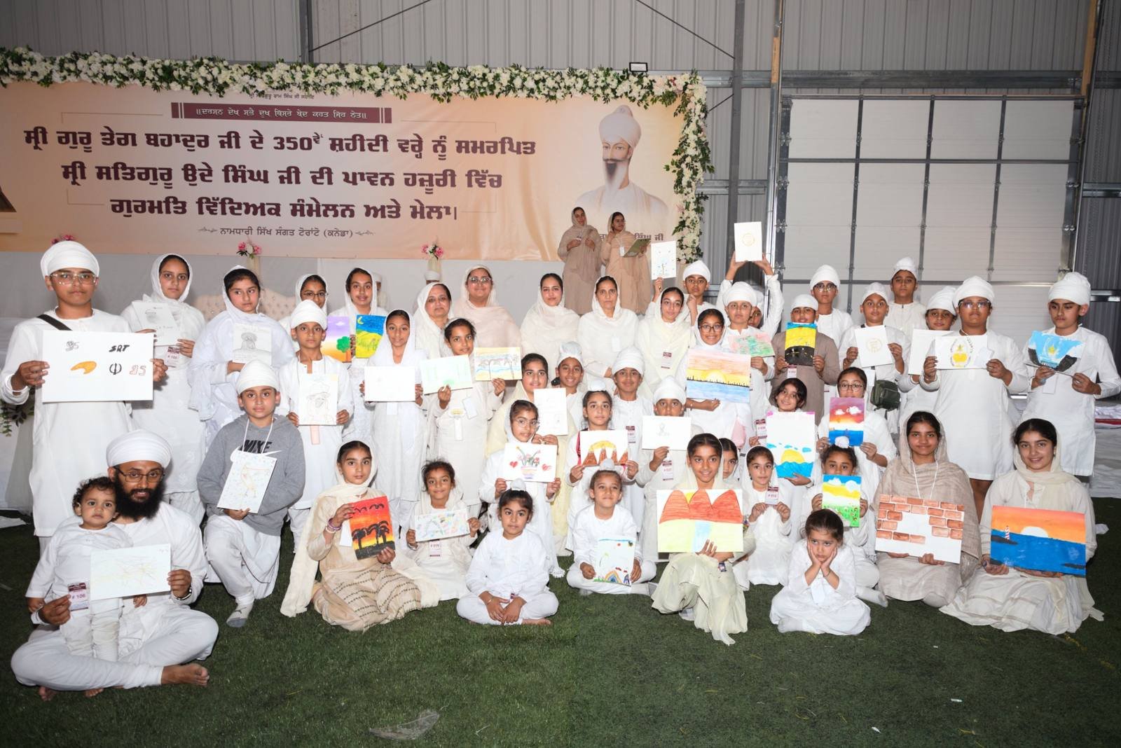 Children holding up their paintings from the art competition