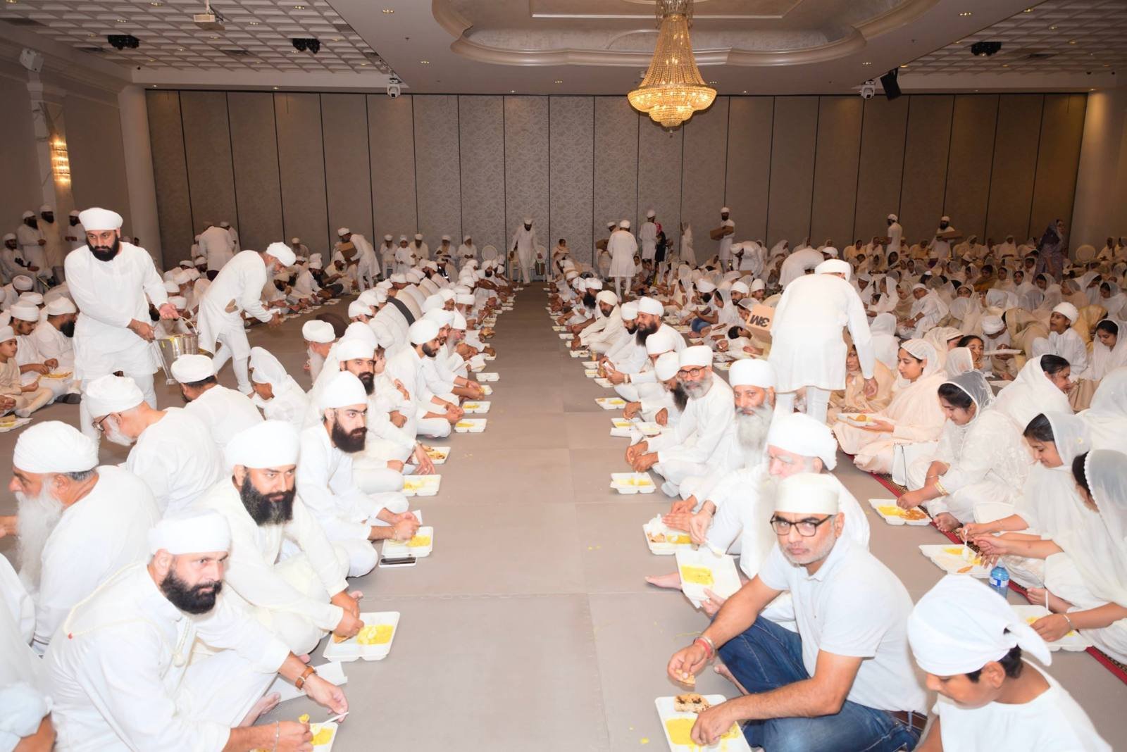 Sangat seated in rows eating langar